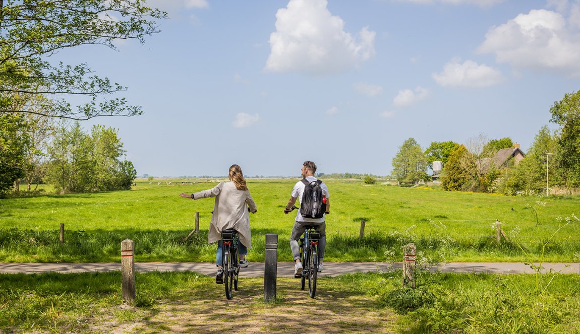 Stel fiets door het Friese landelijk gebied en steekt hand uit